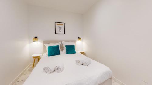 - une chambre blanche avec un lit blanc et des oreillers bleus dans l'établissement Appartements modernes avec véranda, à Strasbourg
