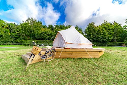a boat with a tent and a bike in a field at Ferry House Holidays in New Ross