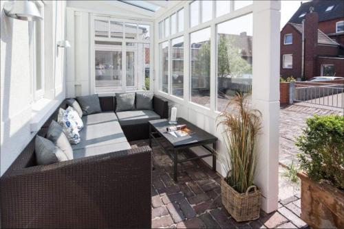 a screened in porch with a couch and a table at Kapitänshaus 1935 in Norderney