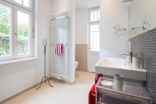 a white bathroom with a sink and a toilet at Kapitänshaus 1935 in Norderney