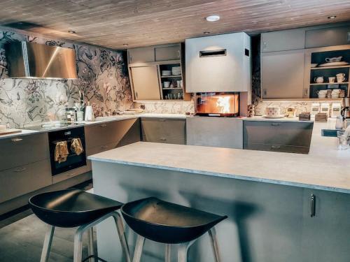 a kitchen with two black stools at a counter at Peaceful Oasis. Panoramic forest- & mountain view. Sauna. in Beitostøl