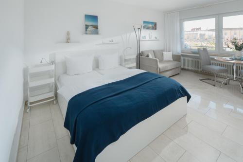 um quarto branco com um cobertor azul numa cama em Haus Dünenrose - Dünnenest em Norderney