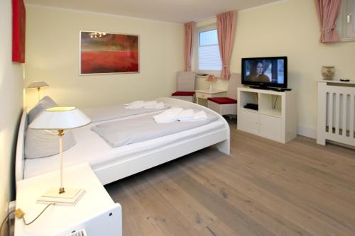 una camera da letto con un grande letto bianco e una televisione di Am Gruenstreifen 33_ Whg_ 8 _Klein a Wyk auf Föhr