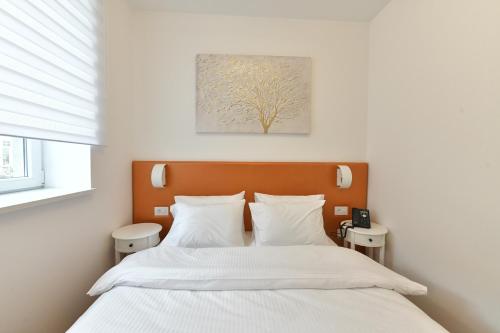 a bedroom with a bed with white sheets and a tree painting at Royal Wellness and Spa in Ruma
