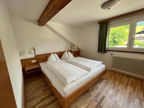 Schlafzimmer mit einem Bett mit weißer Bettwäsche und einem Fenster in der Unterkunft Appartements-Restaurant Schwaiger in Tauplitz