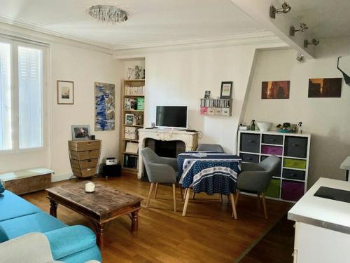 ein Wohnzimmer mit einem blauen Sofa und einem Tisch in der Unterkunft Appartement à Montmartre in Paris