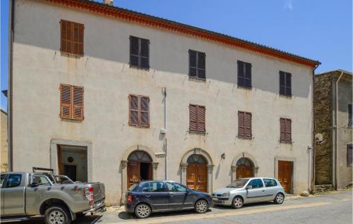 Deux voitures garées devant un grand bâtiment dans l'établissement 1 Bedroom Amazing Apartment In Ghisoni, à Ghisoni