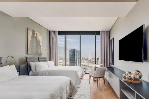 a hotel room with two beds and a flat screen tv at Grand Fiesta Americana Monterrey Valle in Monterrey