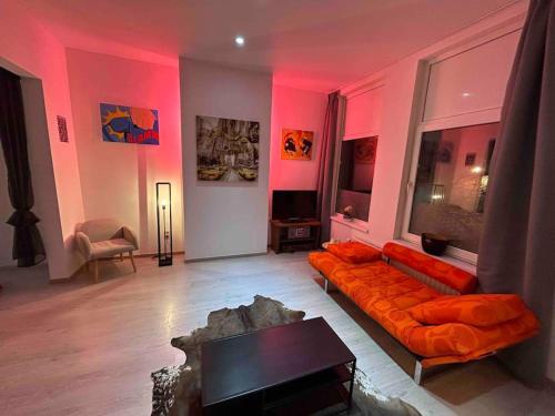 ein Wohnzimmer mit orangefarbener Couch und rosafarbener Beleuchtung in der Unterkunft Antwerp City apartment 2 in Antwerpen