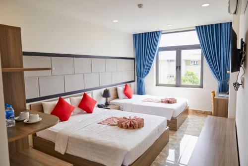 a hotel room with two beds with red pillows at Khang Thịnh Hotel Long Thành in Long Thành