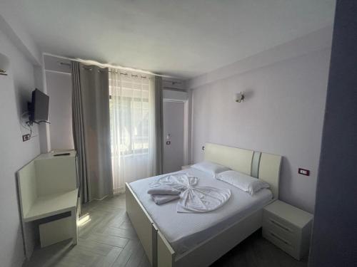 a white bed in a room with a window at Hotel Ferrara in Durrës