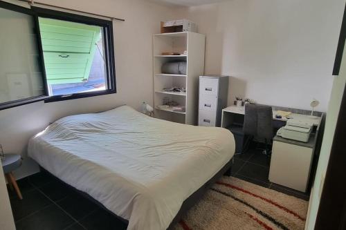um quarto com uma cama, uma secretária e uma janela em Charmant T2 Saint-Leu- Proche lagon et commerces ! em Saint-Leu