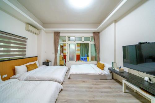 a hotel room with two beds and a flat screen tv at 向晴民宿 花蓮市包棟民宿 in Hualien City