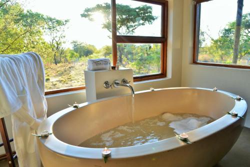 uma banheira cheia de água em frente a uma janela em Safari Plains em Mabula
