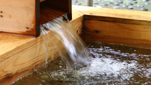 a stream of water coming out of a wooden box at 丸山鉱泉旅館 in Nitanzawa