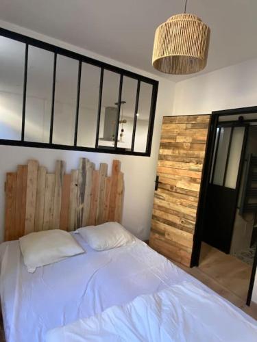 ein Schlafzimmer mit einem weißen Bett und einer Holzwand in der Unterkunft T2 4 places 4min à pied Château in Pau