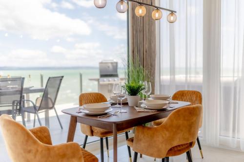 a dining room with a table and chairs and the ocean at LelleMarine by BLTN Apartmanok Balatonlelle in Balatonlelle