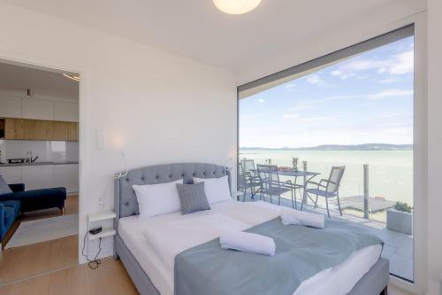 a bedroom with a bed and a view of the ocean at LelleMarine by BLTN Apartmanok Balatonlelle in Balatonlelle