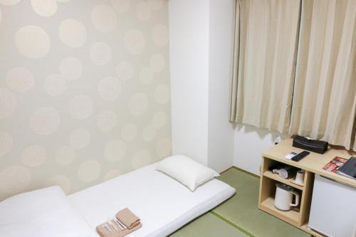 a small room with a bed and a window at Hotel Shin-Imamiya in Osaka