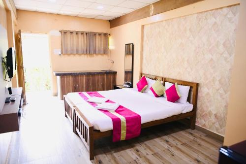 a bedroom with a large bed with pink pillows at Lighthouse Waterpark and Resort in Mansar