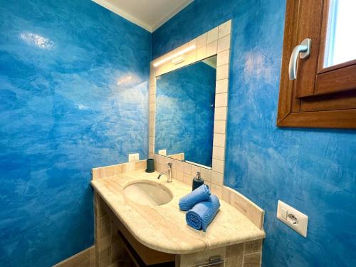 a blue bathroom with a sink and a mirror at Villa Azzurra in Monte Petrosu