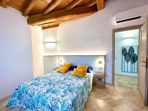a bedroom with a bed with blue and yellow pillows at Villa Azzurra in Monte Petrosu
