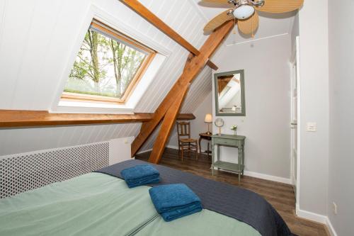 a attic bedroom with a bed and a window at Hoeve Suydeinde in Aarlanderveen