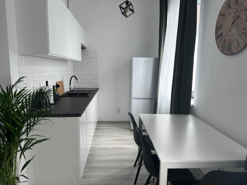 a white kitchen with a table and a white refrigerator at Apartamenty Przy Deptaku in Świnoujście