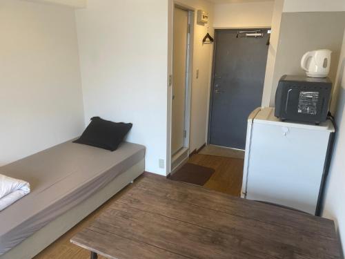 a small room with a bed and a refrigerator at Morinomiya Flat 森ノ宮フラット in Osaka