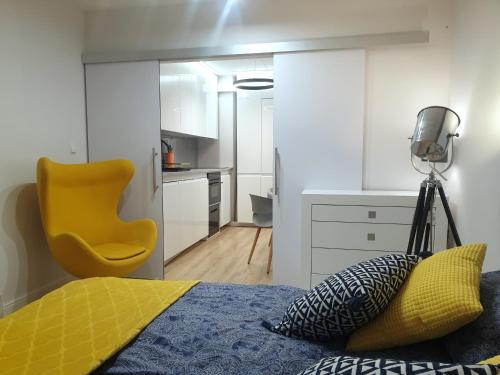 een slaapkamer met een bed en een gele stoel bij APARTAMENT AIRPORT 132 in Warschau