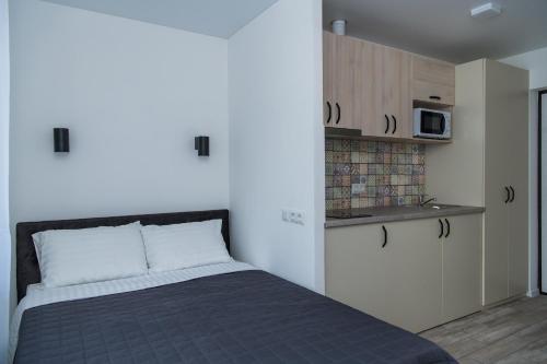 a bedroom with a bed and a kitchen with a microwave at Апартаменти MYFREEDOM поруч із метро Шулявська in Kyiv