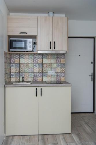a kitchen with white cabinets and a microwave at Апартаменти MYFREEDOM поруч із метро Шулявська in Kyiv