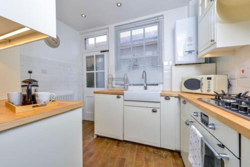 a kitchen with white cabinets and a sink at Victorian townhouse - Stamford centre - 2 big bedrooms, living room kitchen etc tastefully decorated in Stamford