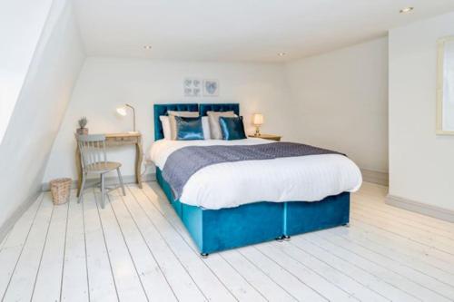 a bedroom with a blue bed with a desk and a chair at Victorian townhouse - Stamford centre - 2 big bedrooms, living room kitchen etc tastefully decorated in Stamford