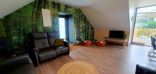 a living room with a couch and a tv at La Maison du Sabotier in Custinne