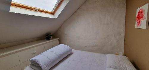 een slaapkamer met een wit bed en een raam bij La Maison du Sabotier in Custinne