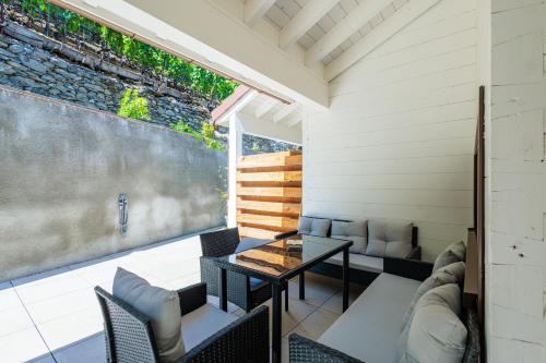 a patio with a table and chairs and a wall at Villa mitoyenne proche des bains in Saillon