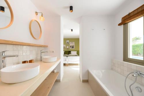 a bathroom with two sinks and a tub and a mirror at Villa Maria - Luxury Getaway in Ses Paisses