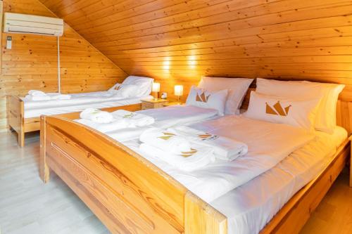 2 lits dans une cabane en bois avec des draps blancs dans l'établissement Bella Mura Nature Chalet I27, à Podčetrtek