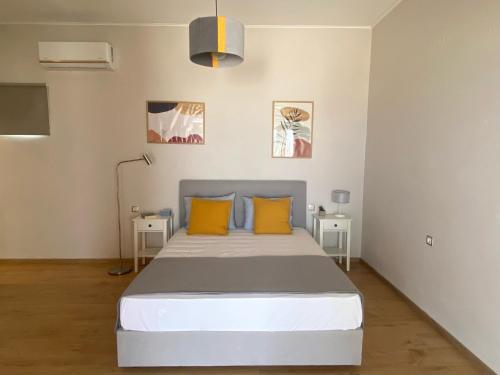 a bedroom with a bed with yellow pillows and two tables at AMMOS Beach apartment in Sidari
