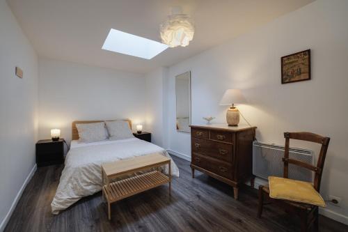 une chambre avec un lit, une commode et une chaise dans l'établissement Appartement proche Jardin Public, à Bordeaux