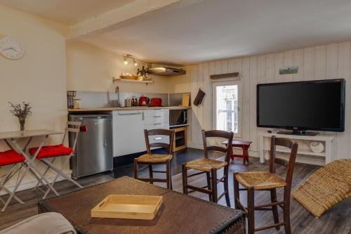un salon avec une télévision, une table et des chaises dans l'établissement Appartement proche Jardin Public, à Bordeaux