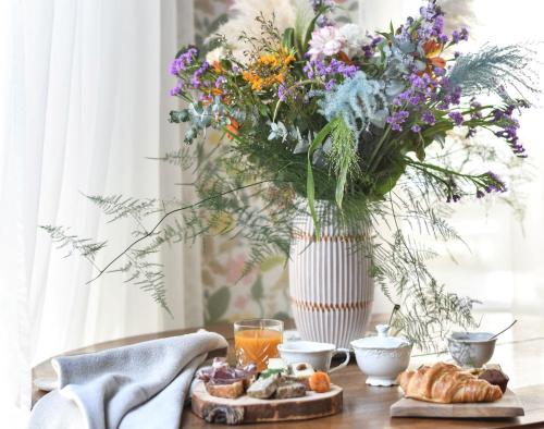 a table with a vase of flowers and a table with food at Hotel Mercure Château de Fontainebleau in Fontainebleau