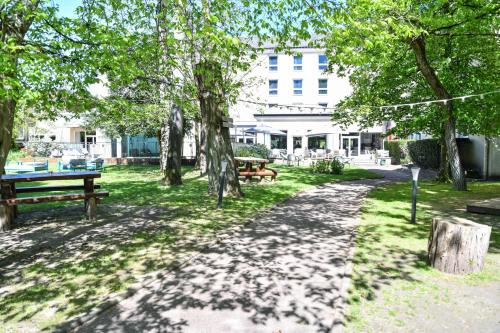 a park with benches and trees and a building at Hotel Mercure Château de Fontainebleau in Fontainebleau