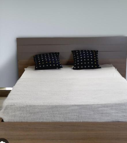 Cama con sábanas y almohadas blancas y negras en Appartement neuf, en Nador
