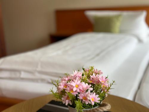 a vase of pink flowers on a table next to a bed at Landhotel Vessens Hoff in Buchholz in der Nordheide