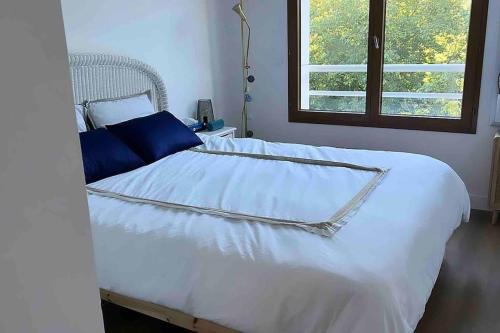 Cama blanca con almohadas azules y ventana en Apartment 2 bedroom with parking, pool and tennis, en Le Chesnay