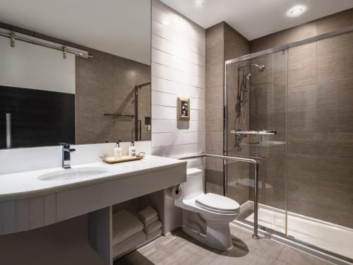 a bathroom with a toilet and a sink and a shower at voco Fiorello - LaGuardia East by IHG in Queens