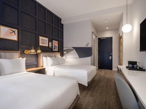 a hotel room with two beds and a corridor at voco Fiorello - LaGuardia East by IHG in Queens