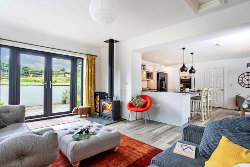 a living room with a couch and a fireplace and a kitchen at Finest Retreats - Quarry Lodge in Wigton